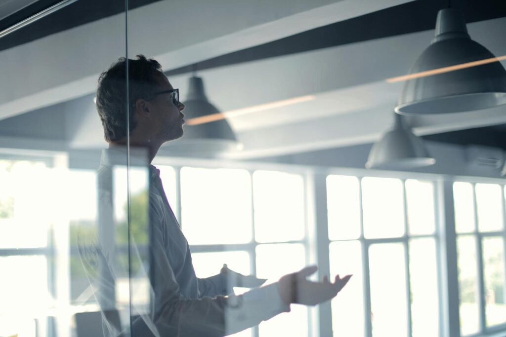 Man gesturing in modern office with large windows.
