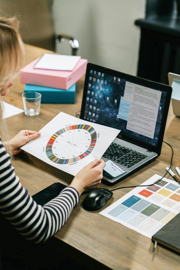 Woman analyzing color wheel beside computer desk.