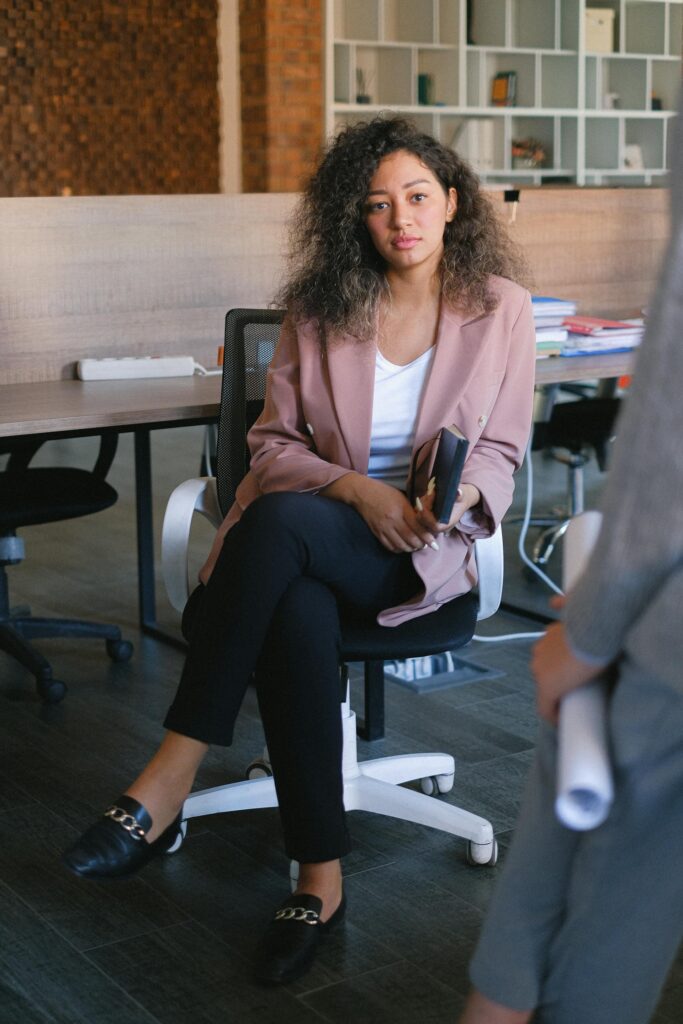 Businesswoman sitting in office chair with smartphone.