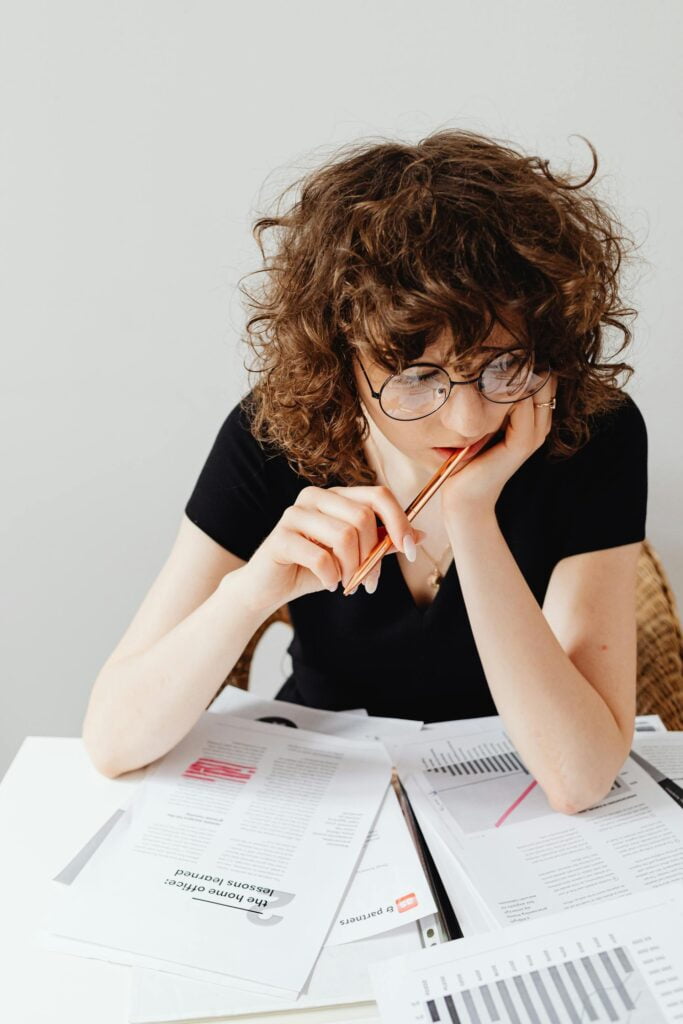 Woman reviewing documents with pencil and glasses.