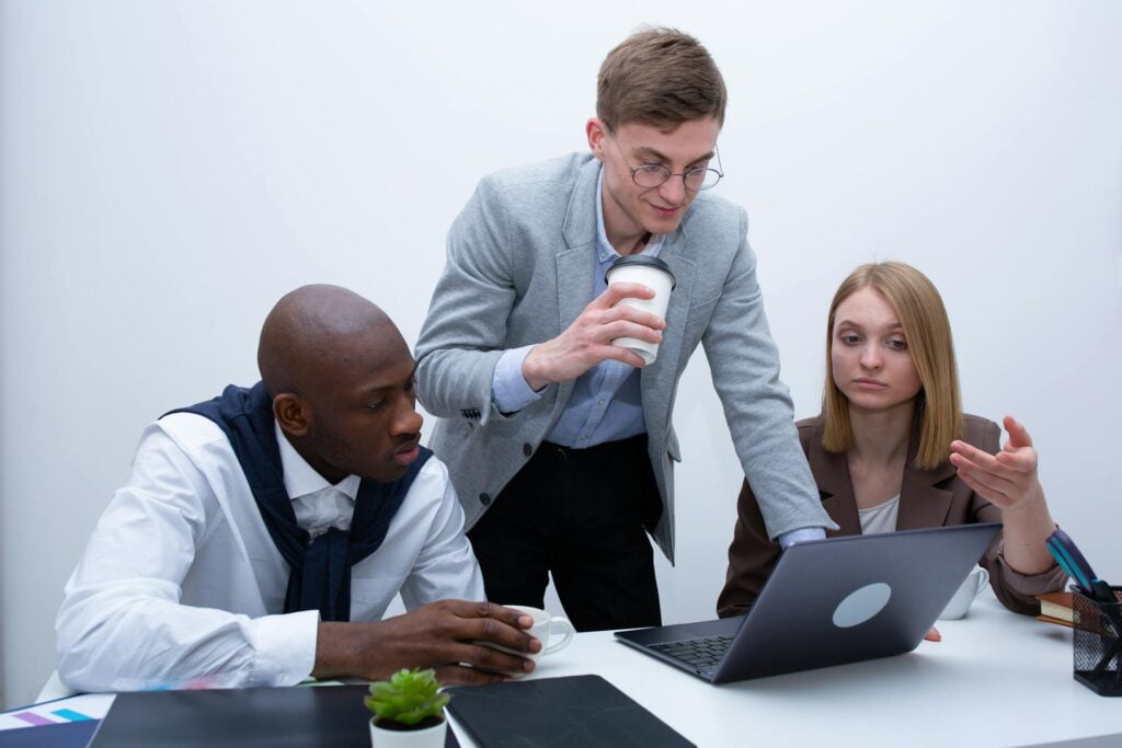 Business team discussing work on laptop in office.