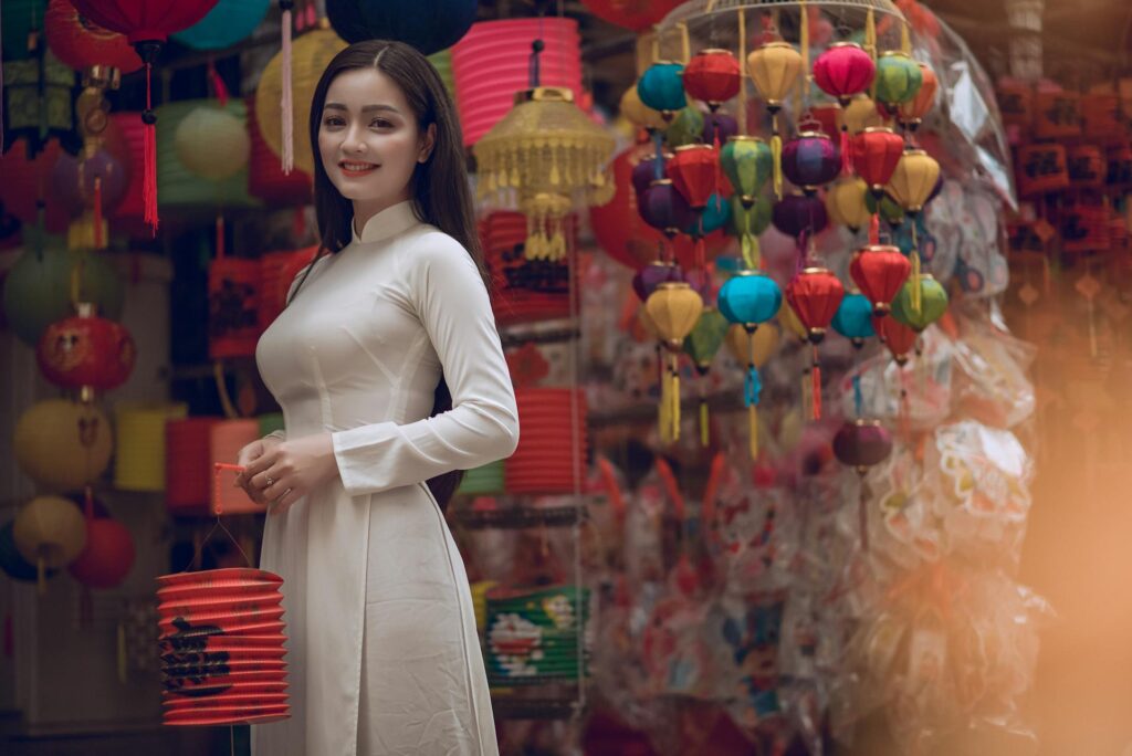 Woman in traditional dress among colorful lanterns.