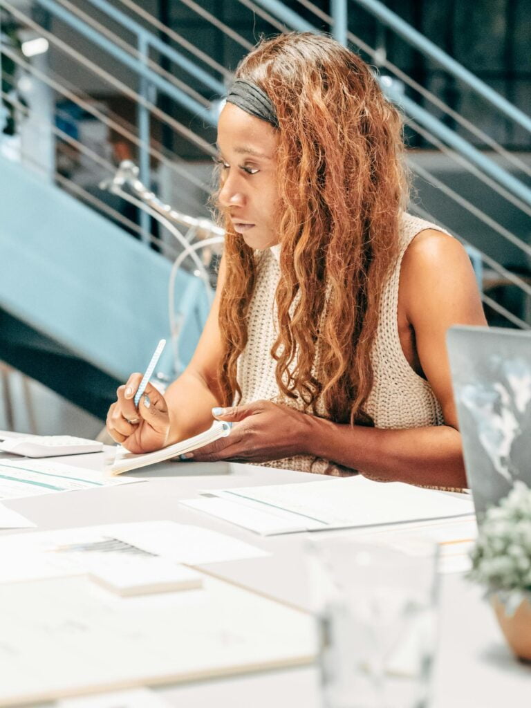 Woman focused on writing at modern office desk.