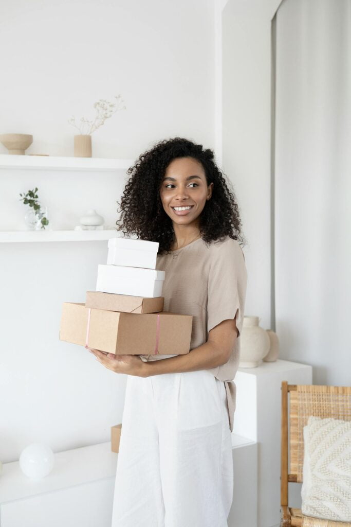 Woman smiling holding stack of boxes in bright room