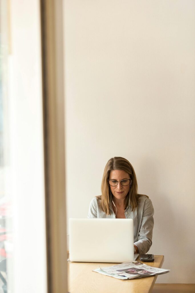 Woman working on laptop in bright office setting.