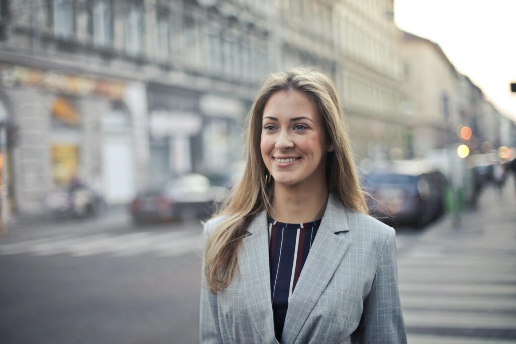 Smiling woman in business attire on city street.