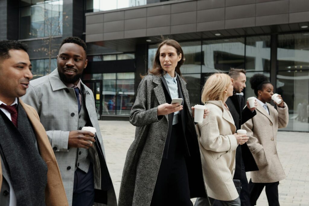 Professionals walking, drinking coffee, urban setting.