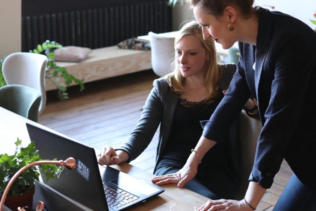 Two women collaborating on a laptop in an office setting.
