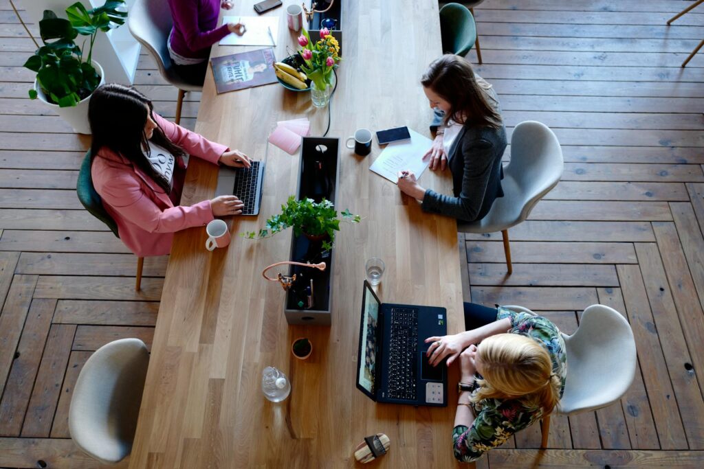 Coworkers in collaborative office space with laptops and notes.