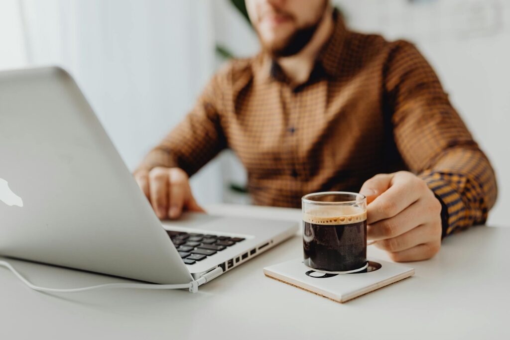 Person working on laptop with coffee.