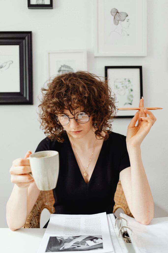 Woman studying with coffee and pen in hand.