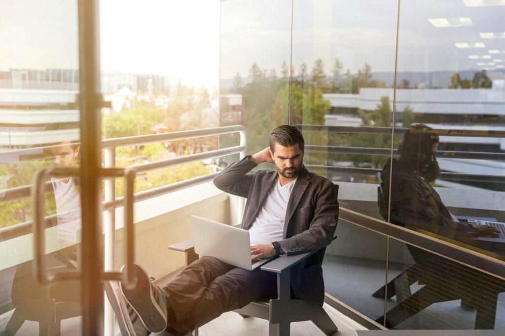 Man working on laptop at modern office balcony.
