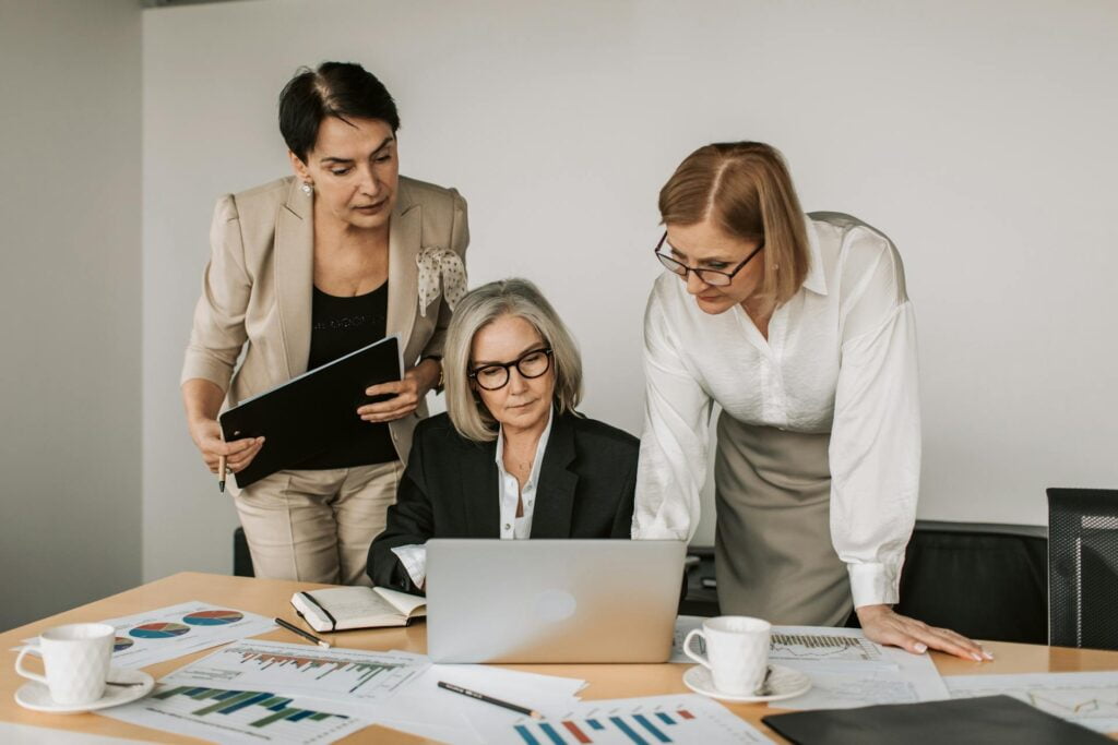 Three professionals analyzing data on computer in office.