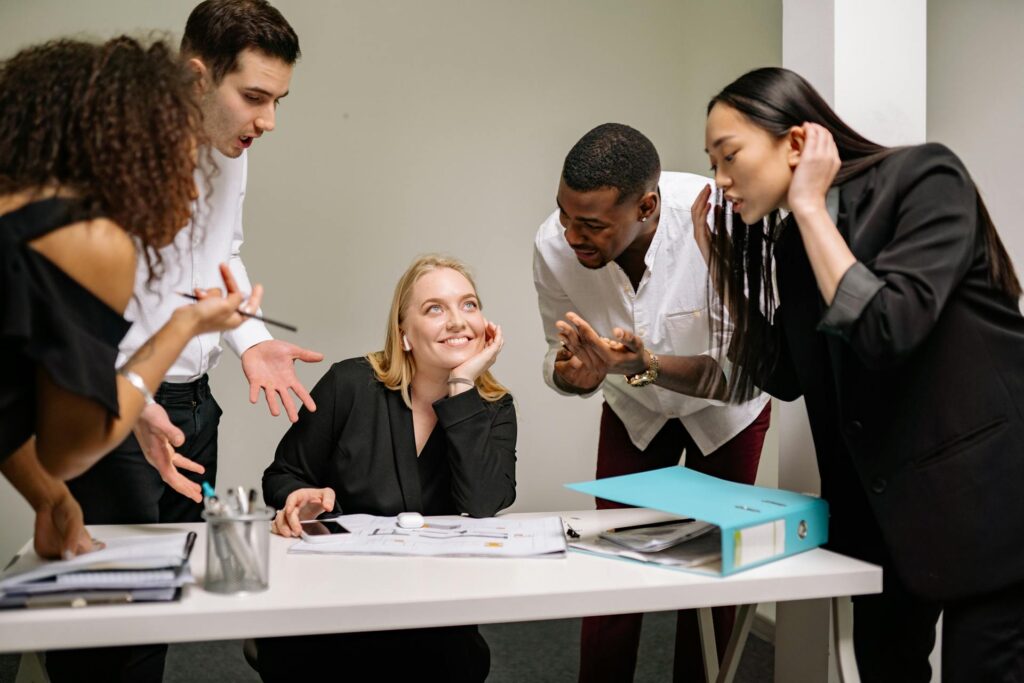 Team discussing project with smiling woman at desk.