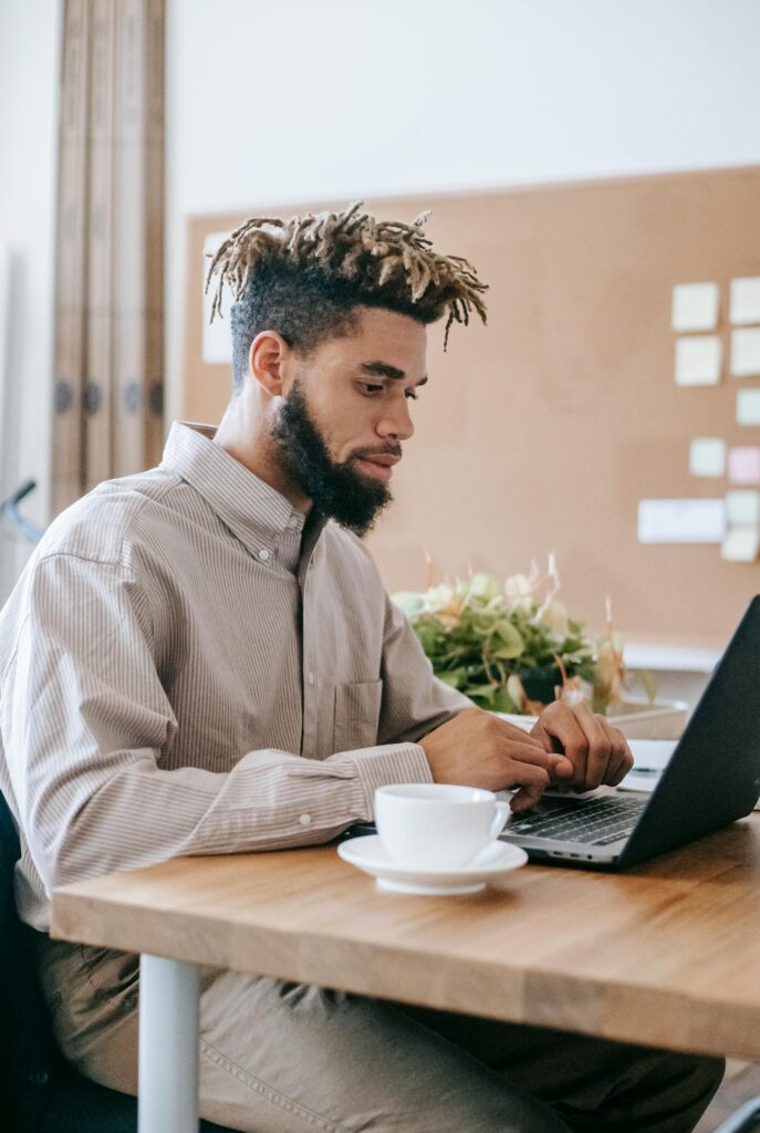 Man working on laptop at a wooden desk.